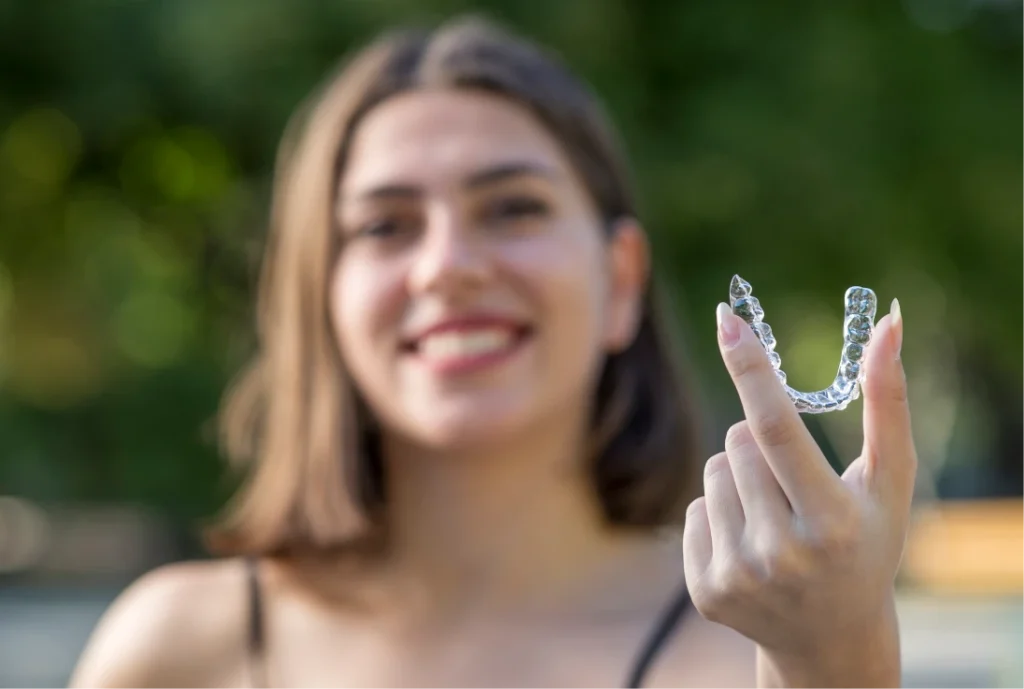 women smiling and holding an Invisalign aligner